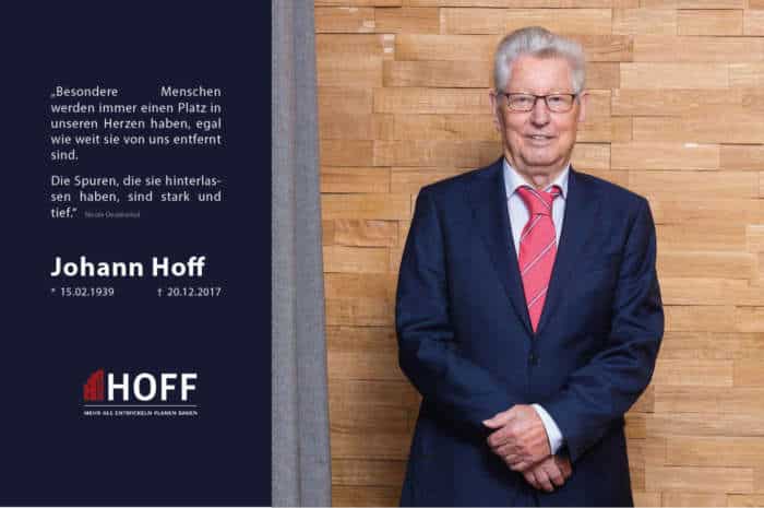 Ein älterer Mann in Anzug und roter Krawatte steht lächelnd vor einer Holzwand. Neben ihm steht sein Name Johann Hoff, sein Geburts- und Sterbedatum, ein Zitat auf Deutsch und das Logo des Bestattungsunternehmens Hoff.