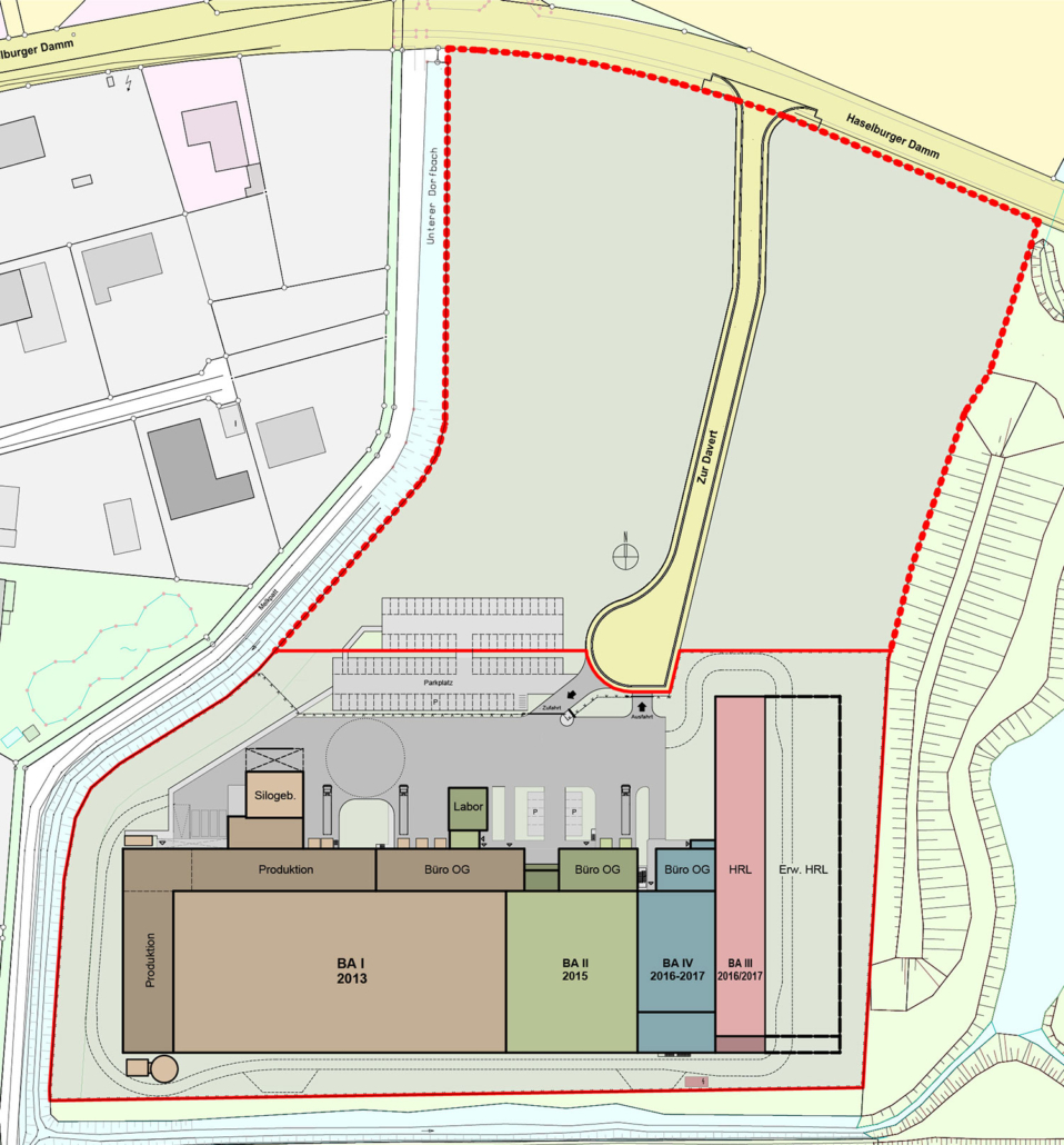 Der Lageplan zeigt einen Komplex mit gekennzeichneten Bereichen für Produktion, Büros, Labore, Parkplätze und Lager, begrenzt durch eine gestrichelte rote Linie. Straßen und umliegende Gebäude sind eingezeichnet, Bäume und Grünflächen umgeben das Gelände.