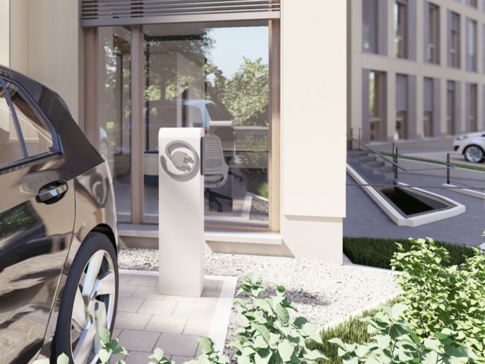 Ein schwarzes Elektroauto parkt an einer Ladestation vor einem modernen Gebäude mit großen Fenstern, Grünflächen im Vordergrund und einem weiteren Auto in der Nähe – eine ideale Szene für nachhaltiges Bauen und umweltfreundliches Stadtleben.