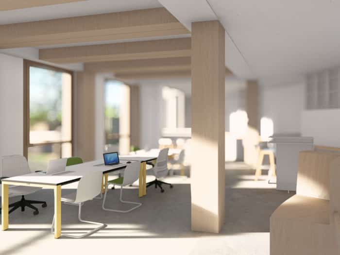 Ein moderner, lichtdurchfluteter Büroraum im Sinne des nachhaltigen Bauens mit großen Fenstern, Holzbalken, weißen Wänden und mehreren Schreibtischen. Laptops und Stühle sind an den Arbeitsplätzen angeordnet, und der Raum ist von natürlichem Licht durchflutet.